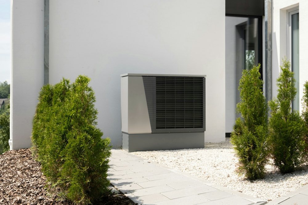 Außeneinheit einer Wärmepumpe neben einem modernen Wohnhaus